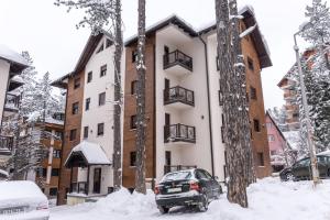 a apartment building with snow in front of it at Apartments Mikic Zlatibor in Zlatibor