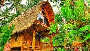 a thatch roofed house with a thatched roof at Tetebatu Sama Sama Bungalows in Tetebatu