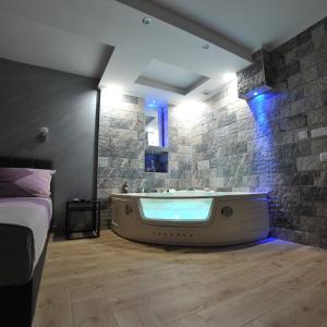 a large bath tub in a room with a stone wall at Wonderland spa free parking in Niš +52 photos