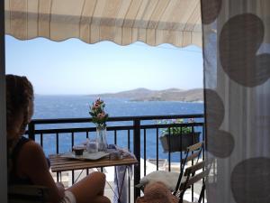 a woman sitting at a table with a view of the ocean at SEA BREEZE-VAPORIA-SYROS in Ermoupoli
