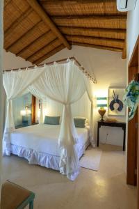 a bedroom with a white bed with a canopy at Etnia Casa Hotel in Trancoso