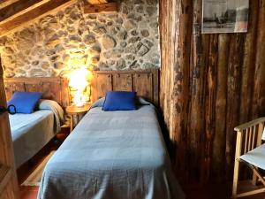 sypialnia z 2 łóżkami i kamienną ścianą w obiekcie Casona de Saltus, espectacular casona en Sotosalbos,10min de Segovia w mieście Sotosalbos