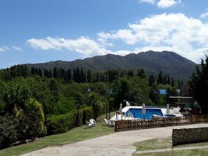 una casa con una valla y montañas en el fondo en COMPLEJO DEL MIRADOR con piscina climatizada en Potrero de los Funes