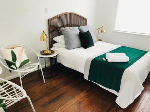 1 dormitorio con 1 cama con manta verde y silla en Tea Gardens Hotel en Tea Gardens