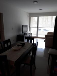 ein Wohnzimmer mit Tisch und Stühlen und einem Fernseher in der Unterkunft La mansa in Puerto Madryn