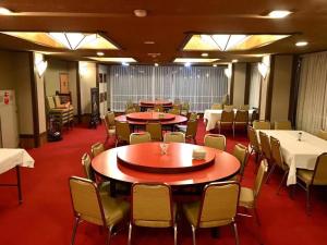a dining room with tables and chairs and white tablecloths at Rakki OnsenRyokan 楽奇温泉旅館 in Yamanouchi