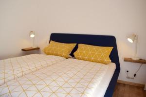 un lit avec des draps jaunes et blancs et deux lampes dans l'établissement FERIENWOHNUNG AM GEISBERG, à Geisfeld