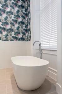 a white bath tub in a bathroom with a floral shower curtain at The Lane Hotel in Edinburgh