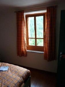 Schlafzimmer mit einem Bett und einem Fenster in der Unterkunft Agriturismo Plan Da Crosc in Prato Carnico