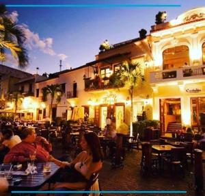 un grupo de personas sentadas frente a un restaurante en Caribbean Hotel Santo Domingo, en Santo Domingo