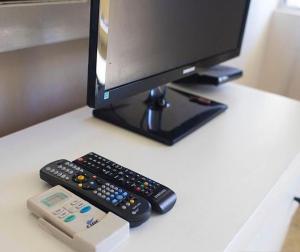 a computer monitor and two remote controls on a desk at Caribbean Hotel Santo Domingo in Santo Domingo