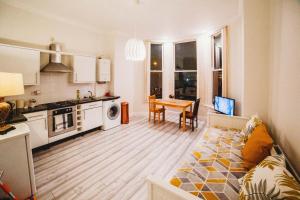 eine Küche und ein Wohnzimmer mit einem Sofa und einem Tisch in der Unterkunft Cosy Apartment in Safe Area in Liverpool