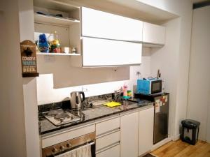 een kleine keuken met witte kasten en een wastafel bij Cozy Apartment in Nuñez in Buenos Aires