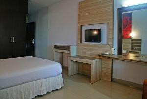 Schlafzimmer mit einem Bett, einem Schreibtisch und einem TV in der Unterkunft HOTEL PRIMA in Makassar