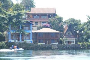 people in a boat in front of a house on the water at Reggae Guest House in Tuk Tuk