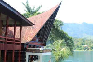 a building with a red roof next to a body of water at Reggae Guest House in Tuktuk Siadong