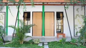 a building with two wooden doors and a bench at Hotel Jogja Kili Suci By Simply Homy in Yogyakarta
