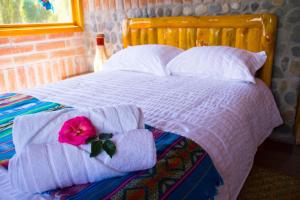 Una cama con toallas y una flor rosa. en Watzara Wasi Cottage Familiar Camprestre Y Lofts en Cotacachi, en Cotacachi