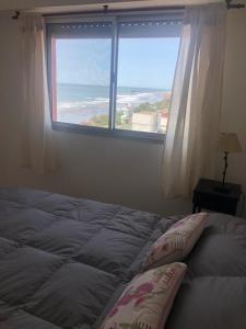 a bed with two pillows sitting in front of a window at Departamento frente al mar in Santa Teresita