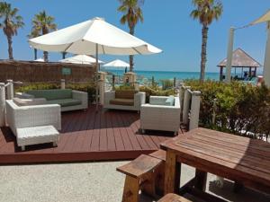 a wooden deck with chairs and an umbrella and a table at AN OCEAN,BEACHFRONT AND POOL VIEW Apartment 210 in Mandurah
