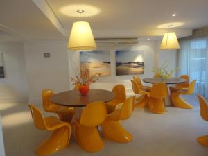 two tables and chairs in a room with yellow chairs at Fortaleza VIP Experience in Fortaleza