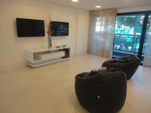a living room with two chairs and a flat screen tv at Fortaleza VIP Experience in Fortaleza