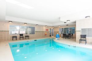 una gran piscina con sillas y una mesa en Holiday Inn Express Hotel & Suites Lagrange I-85, an IHG Hotel, en La Grange