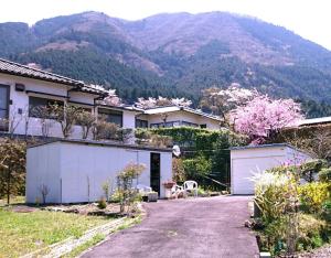 a house with a driveway in front of a mountain at 湯布院月灯り in Yufuin