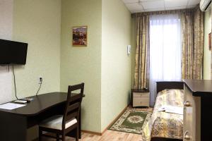 キーロフにあるHotel Preobrazhenskayaのデスク、ベッド、デスク、椅子が備わる客室です。