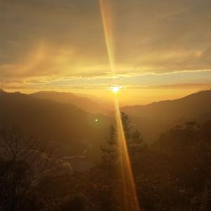 una puesta de sol en las montañas con el sol brillando en Shan Ju Lake Villa, en Renai