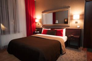 1 dormitorio con cama con almohadas rojas y espejo en Art-Rustic Boutique Hotel, en Chişinău