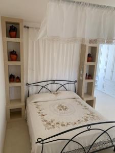 Agriturismo Messer Gesualdo في Nociglia: غرفة نوم بسرير وستارة بيضاء
