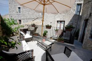 a patio with a table and chairs and an umbrella at Residence Erice Pietre Antiche in Erice