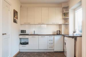 a kitchen with white cabinets and a microwave at Agnės svečių namai in Kaunas