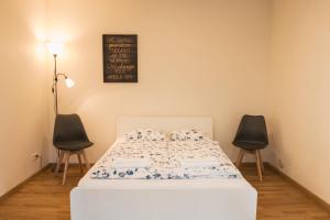 a bed in a room with two chairs and a chalkboard at Agnės svečių namai in Kaunas