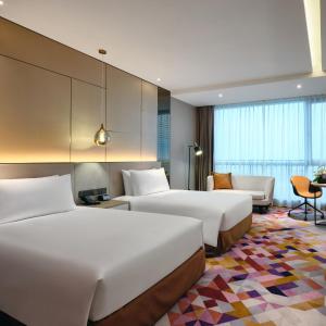 a hotel room with two beds and a couch at The QUBE Hotel Ningbo North in Ningbo