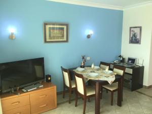 a dining room with a table and a tv at Sharks Bay Oasis Apartment in Sharm El Sheikh