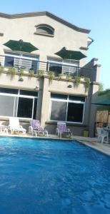 una casa con 2 sillas y una piscina en Pilar Apart Hotel en Pilar