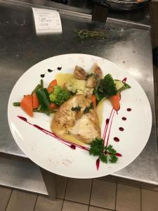 a plate of food with chicken and vegetables on a counter at Motelina in Wattwil +7 photos