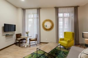 a living room with a yellow chair and a table at DE LA GUARDIA SUITE 1 in Oviedo