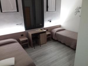 a room with two beds and a table and a mirror at Hotel Alle Scuole NEW in Curtarolo