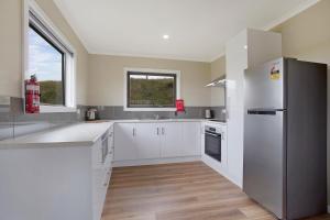 una cucina con armadietti bianchi e frigorifero di Otway coastal villas a Princetown