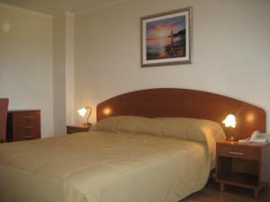 a bedroom with a large bed with two night stands and two lamps at Apartment & Room Angerona in Seget Vranjica