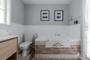 a bathroom with a toilet and a bath tub at Bycroft Lodge in Karaka +73 photos