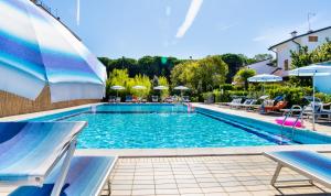a large swimming pool with chairs and umbrellas at Hotel Milano in Eraclea Mare