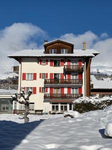 un gran edificio con nieve en el suelo delante de él en Hotel de la Poste Verbier en Verbier