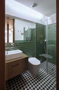ein Badezimmer mit einem Waschbecken, einem WC und grünen Fliesen in der Unterkunft Aparthotel Oporto Batalha in Porto