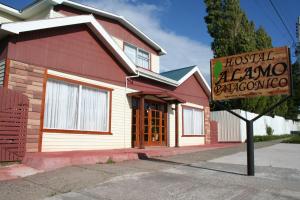 una señal frente a un edificio con una casa en Hostal Alamo Patagonico, en Puerto Natales