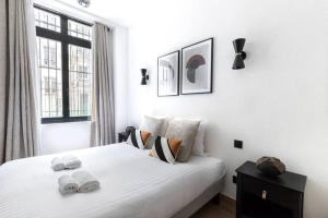 Un dormitorio con una cama blanca con toallas. en HSH Amsterdam St-Lazare Luxury & Design Apartment 6P-2BR, en París