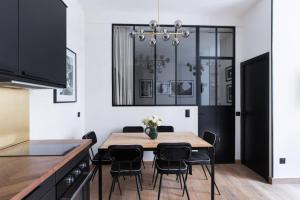 パリにあるHSH Amsterdam St-Lazare Luxury & Design Apartment 6P-2BRのダイニングルーム(テーブル、黒い椅子付)